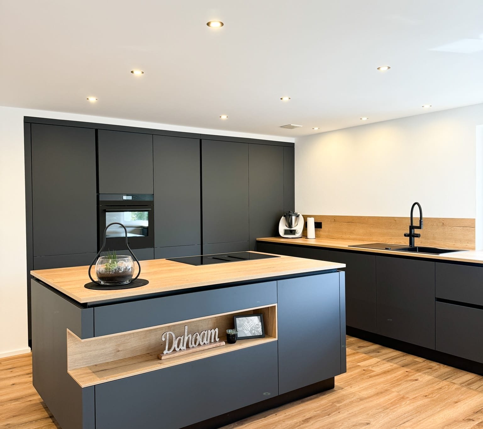Moderne schwarze Küche mit Holzdetails und Kochinsel