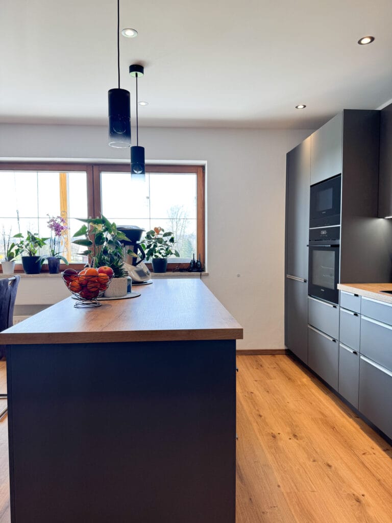 Schwarze Küche mit Holzdetails und großen Fenstern