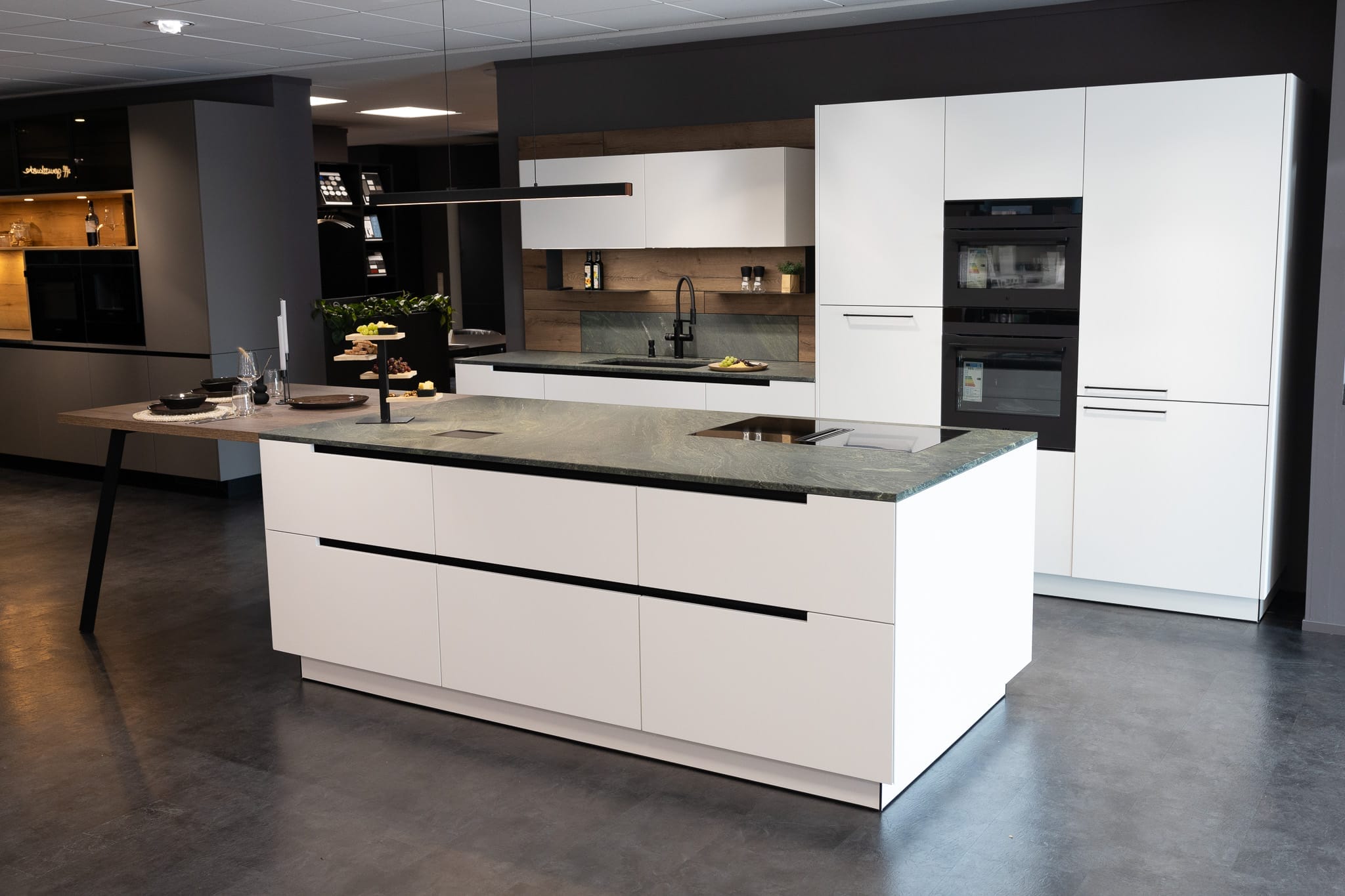 Helle elegante Küche mit Insel und Ausstattung in dunkler Umgebung.