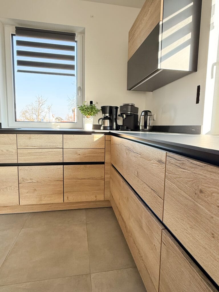 Moderne Holzküche mit Hängeschranken, einem Fenster und Dekoration.